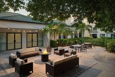 a patio with couches and tables and chairs and trees at Courtyard Miami Airport West Doral in Miami