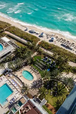 an aerial view of a resort with palm trees and the ocean at Eden Roc Miami Beach in Miami Beach