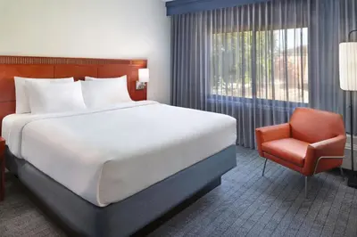 a bedroom with a bed and a chair and a window at Courtyard by Marriott Fort Lauderdale City of Plantation in Plantation