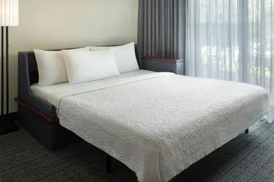 a bedroom with a bed with white sheets and a window at Courtyard by Marriott Fort Lauderdale City of Plantation in Plantation