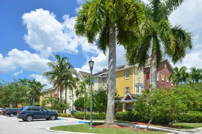 a street with palm trees and a yellow building at Candlewood Suites Miami Lakes by IHG in Miami Lakes