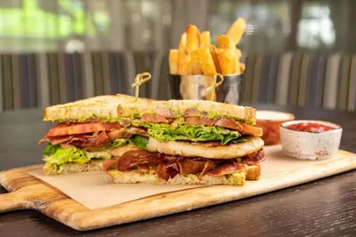 a large sandwich on a cutting board with french fries at Courtyard by Marriott Fort Lauderdale Airport & Cruise Port in Dania Beach