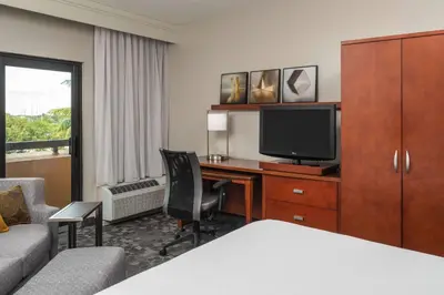 a hotel room with a desk with a television and a bed at Sonesta Select Miami Lakes in Miami Lakes