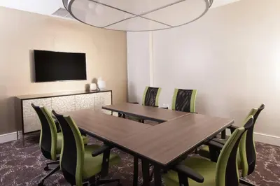a dining room with a wooden table and green chairs at Courtyard Miami Coral Gables in Miami