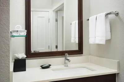 a bathroom with a sink with a mirror and towels at Residence Inn by Marriott Fort Lauderdale City of Plantation in Plantation