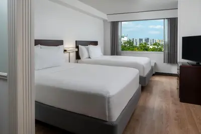 two beds in a hotel room with a window at SpringHill Suites Fort Lauderdale Airport in Dania Beach