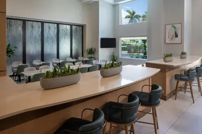 a waiting area with chairs and tables and a waiting room at SpringHill Suites Fort Lauderdale Airport in Dania Beach