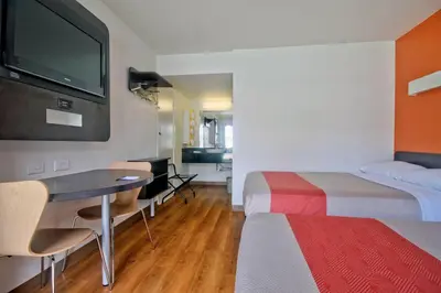 a hotel room with two beds and a table and a tv at Motel 6 Dania Beach in Dania Beach