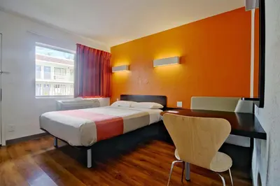 a hotel room with a bed and a desk and a desk at Motel 6 Dania Beach in Dania Beach