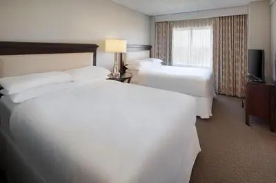 a hotel room with two beds and a television at Sheraton Suites Fort Lauderdale West in Plantation