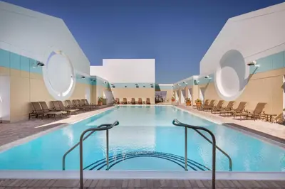 a large swimming pool in a hotel with chairs at Sheraton Suites Fort Lauderdale West in Plantation
