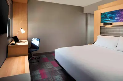 a bedroom with a white bed and a desk and a chair at Aloft Coral Gables in Miami