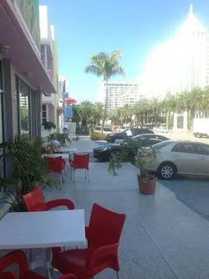 a patio with red chairs and tables on a sidewalk at Collins Avenue Hostel in Miami Beach