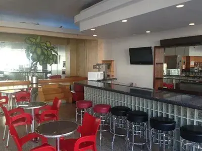 a restaurant with red chairs and tables and a bar at Collins Avenue Hostel in Miami Beach