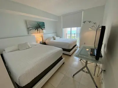 a bedroom with two beds and a television on a table at The King David Condos in Miami Beach
