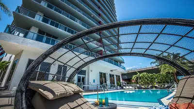 a resort with a swimming pool with a rattan canopy over a swimming pool at Three-Bedroom Beachwalk Resort Apartment in Hallandale Beach