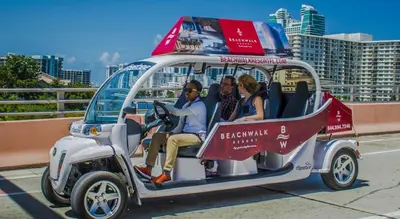a group of people riding in a golf cart at Three-Bedroom Beachwalk Resort Apartment in Hallandale Beach