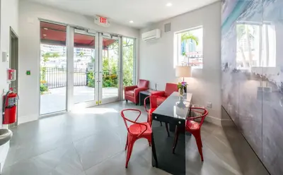 a living room with red chairs and a table at Costa Norte Boutique Hotel Miami Beach in Miami Beach