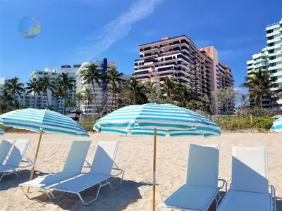 a group of chairs and umbrellas on a beach at Luxury Beach Resort - HORA RENTALS in Miami Beach