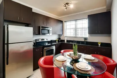 a kitchen with a table with red chairs and a refrigerator at Tradewinds Apartment Hotel Miami Beach in Miami Beach