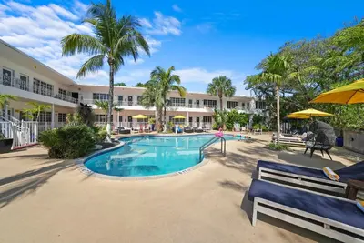 a pool at a resort with palm trees at Tradewinds Apartment Hotel Miami Beach in Miami Beach