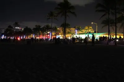 a group of people standing on a beach at night at King condo Fort Lauderdale Central beach in Fort Lauderdale