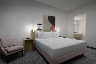 a bedroom with a white bed and a chair at Spark by Hilton Miami Doral in Miami