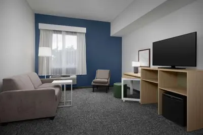 a living room with a tv and a couch and a chair at Spark by Hilton Miami Doral in Miami
