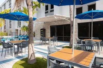 a patio with tables and chairs with blue umbrellas at Hampton Inn Miami-Airport West in Miami