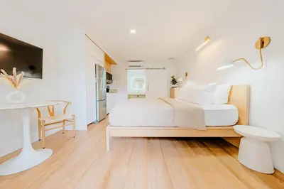 a white bedroom with a bed and a desk at Green Island Inn in Fort Lauderdale