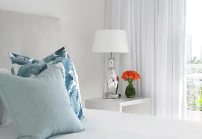 a bed with a lamp and a pillow and a vase with flowers at Grand Beach Hotel Bay Harbor in Miami Beach