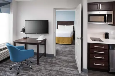 a hotel room with a bed and a desk and a blue chair at Hampton Inn & Suites Miami-Doral Dolphin Mall in Miami