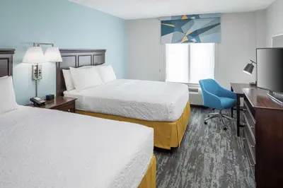 a hotel room with two beds and a desk and a television at Hampton Inn & Suites Miami-Doral Dolphin Mall in Miami