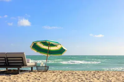 a beach with a chair and an umbrella on the sand at Kimpton Surfcomber Hotel by IHG in Miami Beach