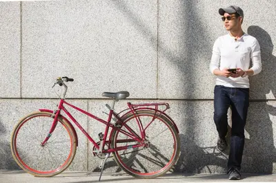 a man is standing next to a red bike at Kimpton Surfcomber Hotel by IHG in Miami Beach
