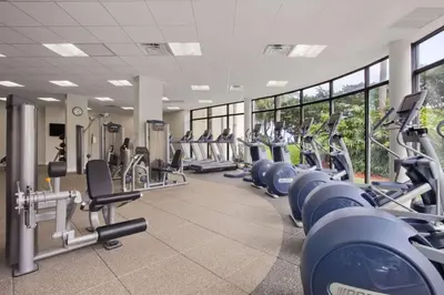 a gym with rows of cardio machines and windows at Hilton Miami Airport Blue Lagoon in Miami
