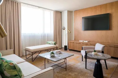 a living room with a couch and a tv at The Dalmar, Fort Lauderdale, a Tribute Portfolio Hotel in Fort Lauderdale