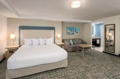 a hotel room with a bed and a couch at Homewood Suites Miami Airport/Blue Lagoon in Miami