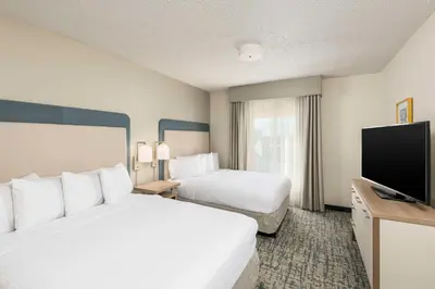 a hotel room with two beds and a flat screen tv at Homewood Suites Miami Airport/Blue Lagoon in Miami