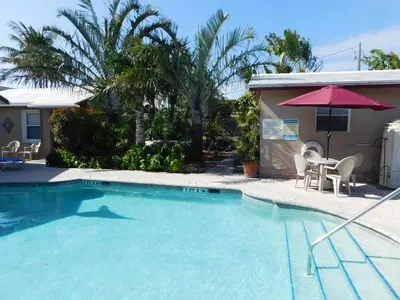 a swimming pool with a table and an umbrella at INN LEATHER GUEST HOUSE-GAY MALE ONLY in Fort Lauderdale