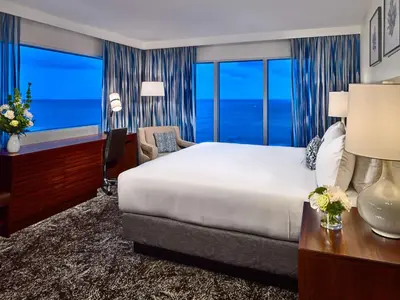 a bedroom with a large bed and a desk with a chair at Sonesta Fort Lauderdale Beach in Fort Lauderdale