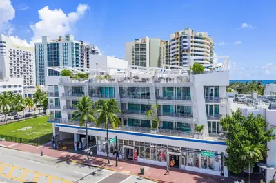 a white building with palm trees in front of tall buildings at Penthouse De Soleil South Beach - on Ocean Drive Miami Beach in Miami Beach