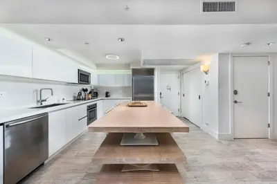 a kitchen with white cabinets and a wooden table at Oceanview Private Condo at 1 Hotel & Homes -1208 in Miami Beach