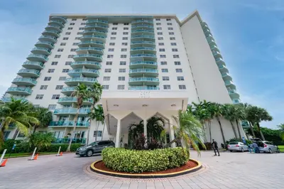 a large white building with palm trees in front of it at Sunny Isles Ocean Reserve Superb Condo Apartments in Miami Beach