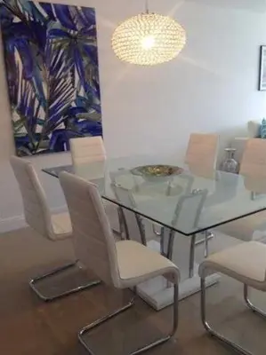 a dining room with a glass table and chairs at Sunny Isles Ocean Reserve Condo Apartments in Miami Beach