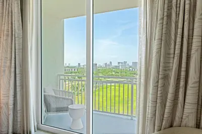 a room with a balcony with a view of the city at JW Marriott Miami Turnberry Resort & Spa in Aventura