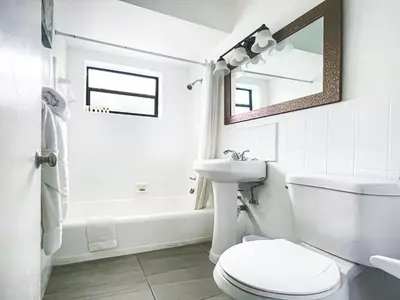 a white bathroom with a toilet and a sink at Silver Spray Motel in Hollywood