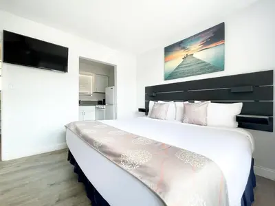 a bedroom with a large white bed with a tv on the wall at Silver Spray Motel in Hollywood