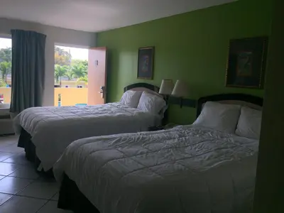 two beds in a room with green walls at Curtis Inn & Suites in Hollywood