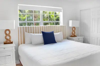 a white bedroom with a large white bed and a window at Coral Reef at Key Biscayne in Miami